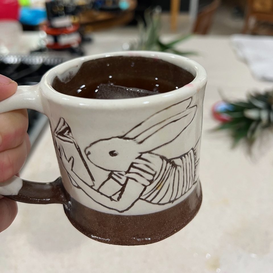 Caption reads "Author marinade." Photo of a small mug carved with a picture of a bunny reading, definitely just tea inside.